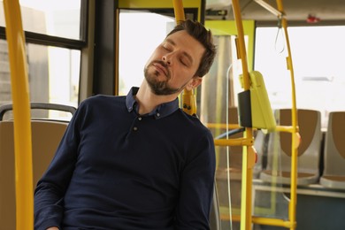 Tired man sleeping while sitting in public transport