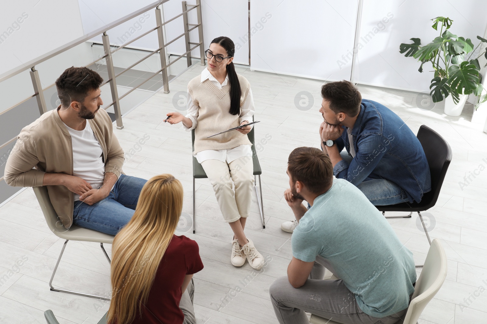 Photo of Psychotherapist working with group of drug addicted people at therapy session indoors