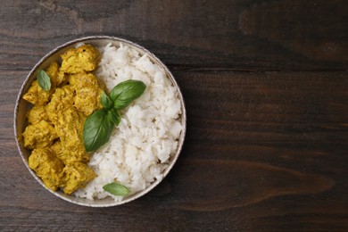 Photo of Delicious rice and chicken with curry sauce on wooden table, top view. Space for text