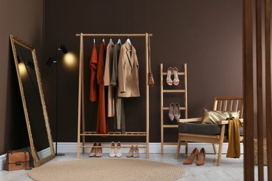 Modern dressing room interior with clothing rack, mirror and comfortable armchair