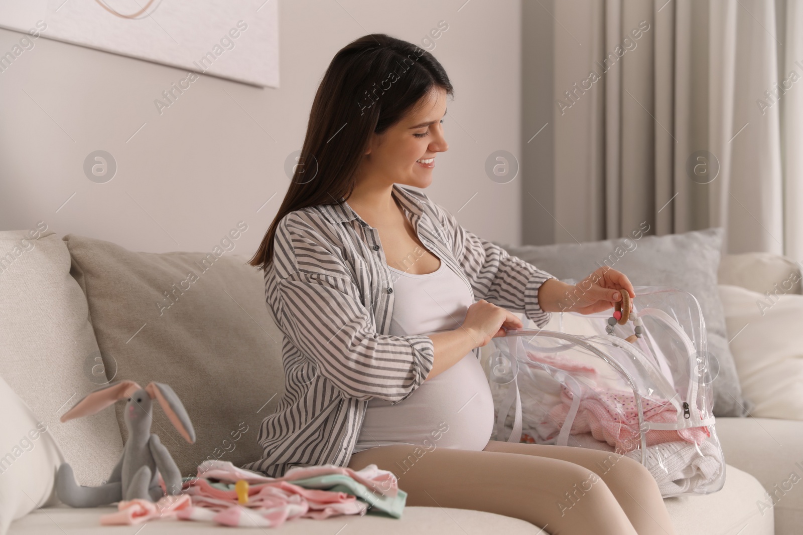 Photo of Pregnant woman packing bag for maternity hospital at home