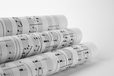 Rolled sheets with music notes on white background, closeup