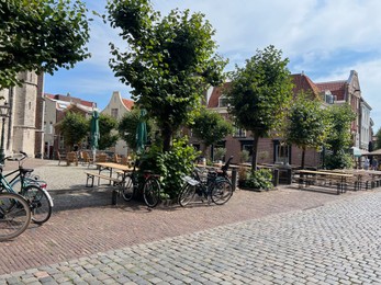 Photo of Beautiful view of parking with bicycles, trees and buildings outdoors on sunny day