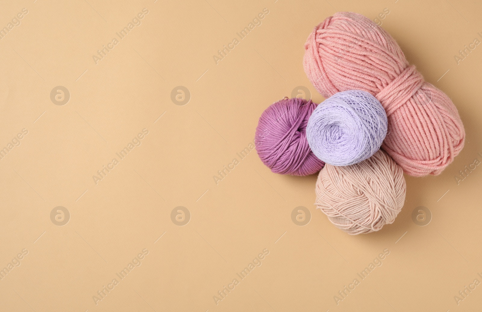 Photo of Soft woolen yarns on beige background, flat lay. Space for text