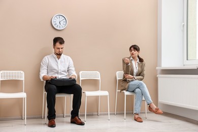 Man and woman waiting for job interview indoors