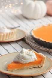 Photo of Piece of fresh homemade pumpkin pie with whipped cream on table