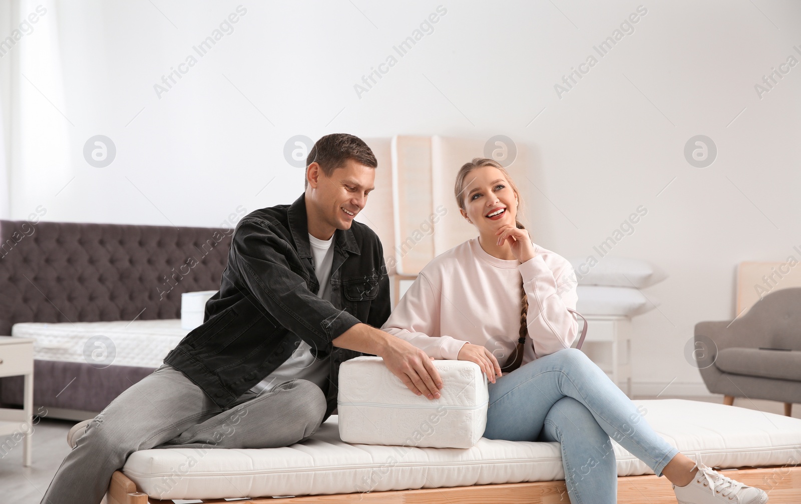 Photo of Happy couple choosing mattress in furniture store