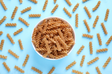 Photo of Flat lay composition with wholemeal fusilli pasta on light blue background