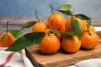 Photo of Wooden board with fresh ripe tangerines on table