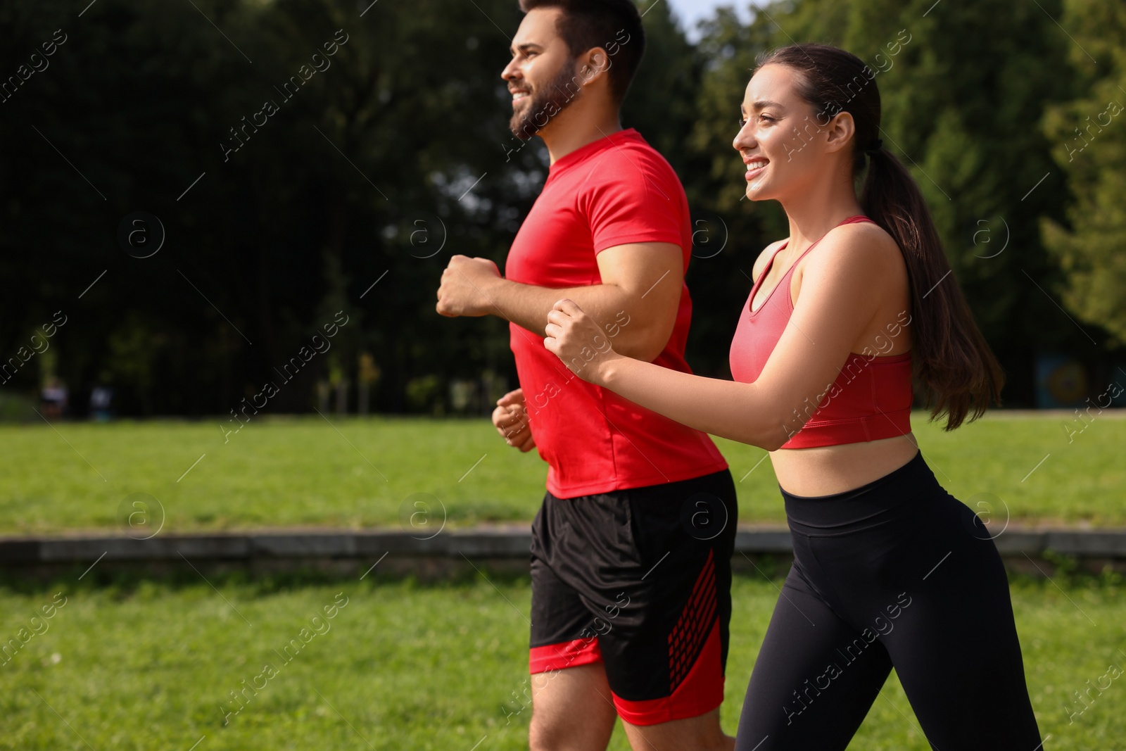 Photo of Healthy lifestyle. Happy couple running in park on sunny day. Space for text