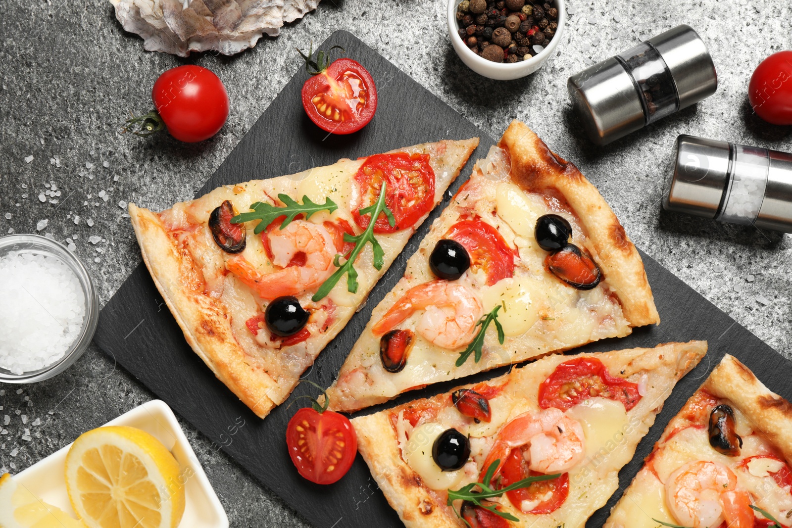 Photo of Tasty pizza with seafood and ingredients on grey table, flat lay