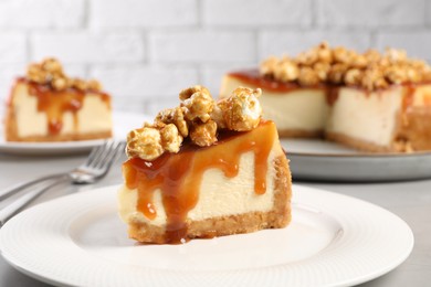 Photo of Piece of delicious caramel cheesecake with popcorn on table, closeup