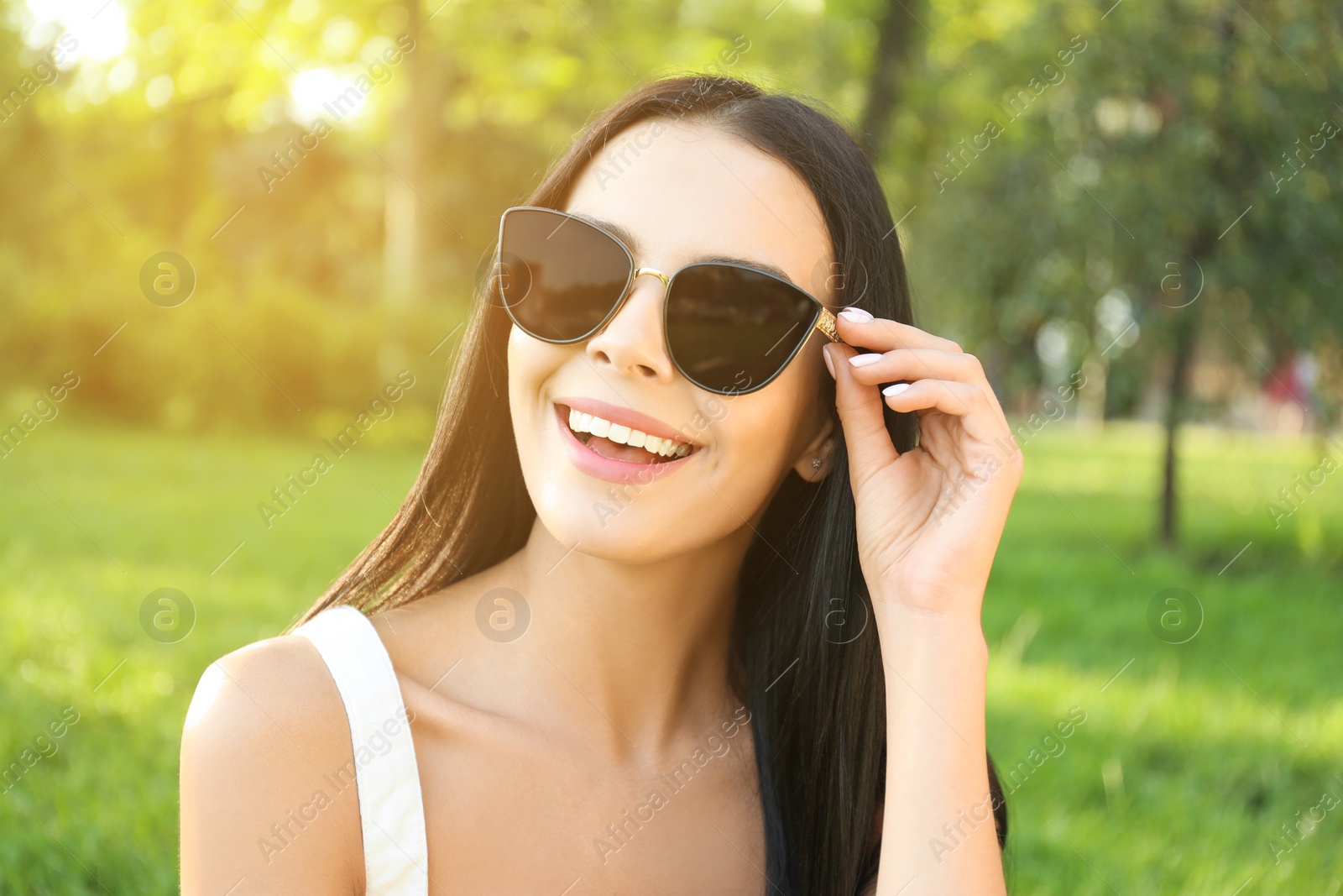 Photo of Beautiful young woman wearing stylish sunglasses in park