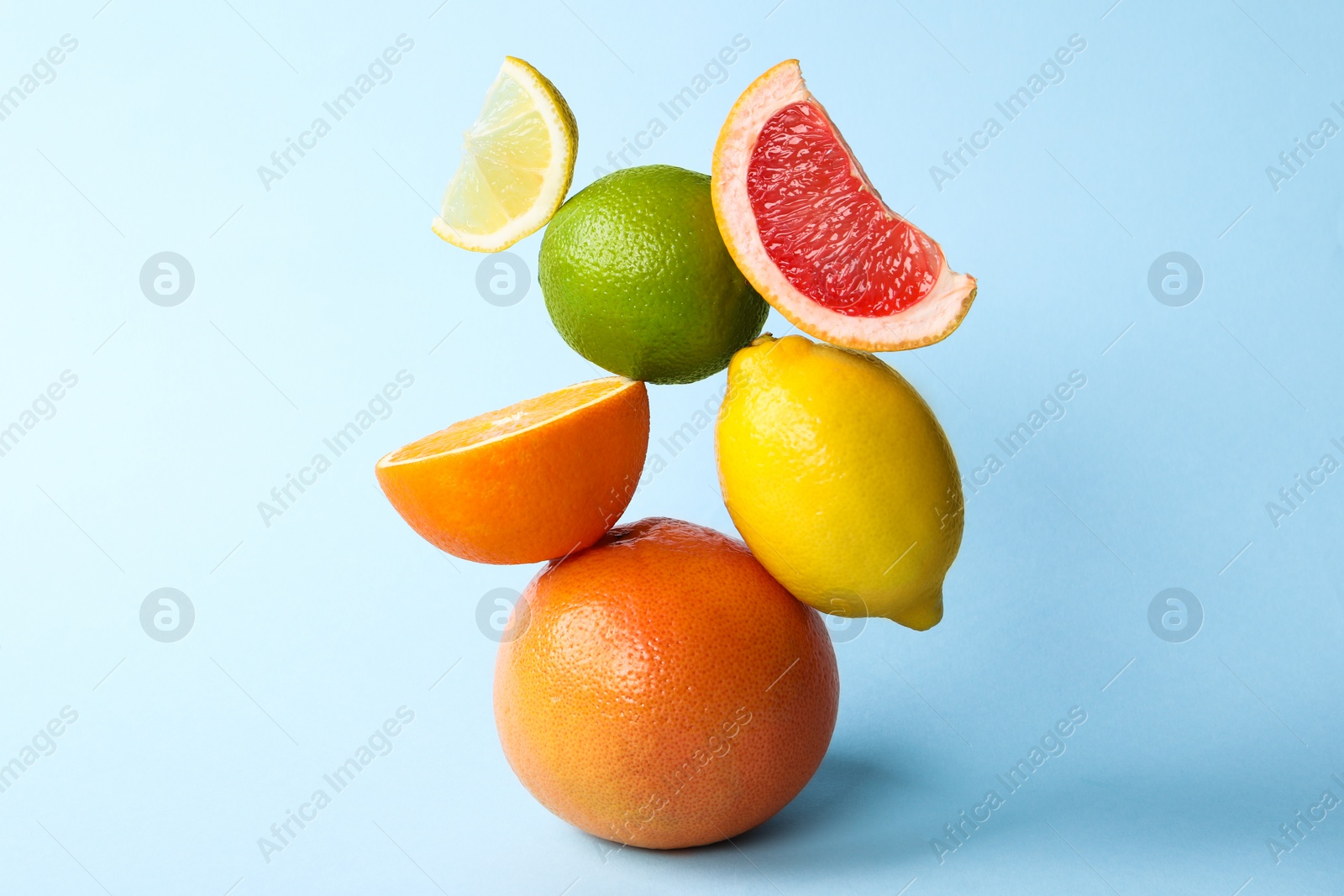 Photo of Fresh ripe citrus fruits on light blue background