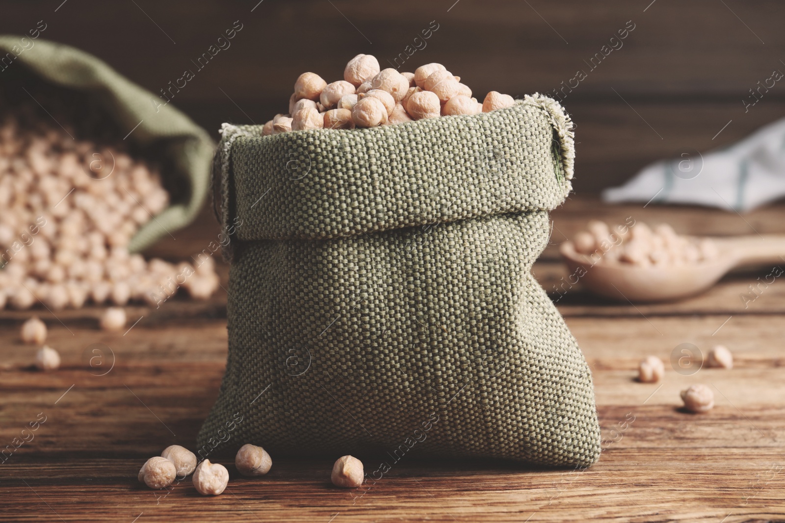 Photo of Sack with chickpeas on wooden table. Natural food