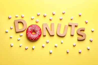 Photo of Flat lay composition with word "Donuts" and marshmallows on color background