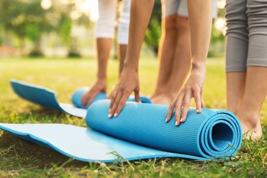 Photo of People rolling up yoga mat in park at morning, closeup