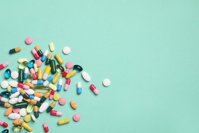 Photo of Many different pills on turquoise background, flat lay. Space for text