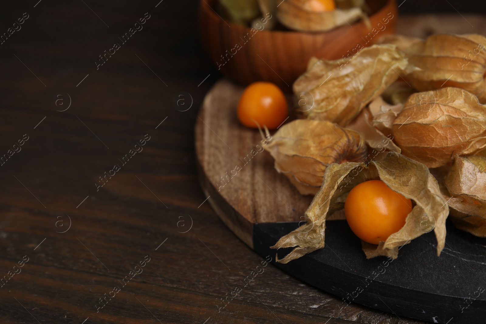 Photo of Ripe physalis fruits with calyxes on wooden table, closeup. Space for text