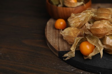 Ripe physalis fruits with calyxes on wooden table, closeup. Space for text