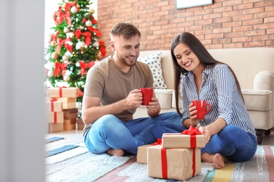 Photo of Happy young couple with Christmas gifts at home