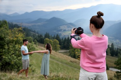 Photo of Professional photographer taking picture of couple in mountains