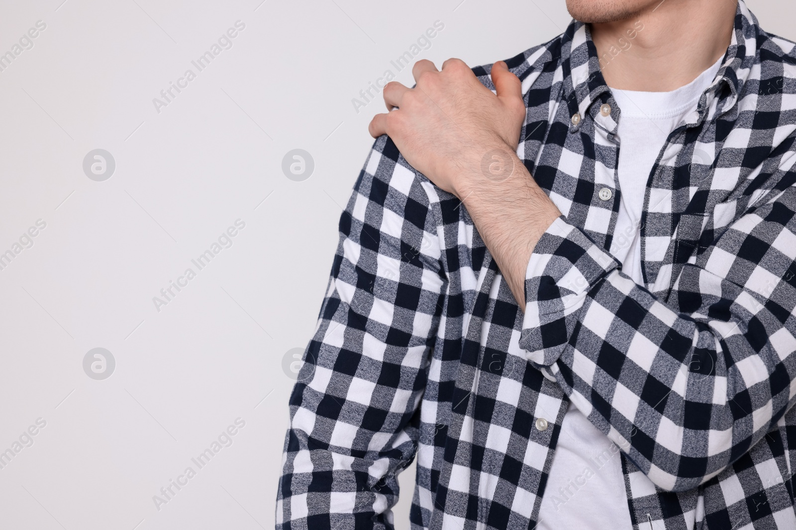 Photo of Man suffering from pain in his shoulder on light background, closeup view with space for text. Arthritis symptoms