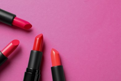 Beautiful lipsticks on pink background, flat lay. Space for text