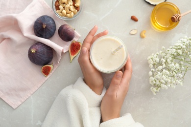 Woman with delicious fig smoothie at light table, top view