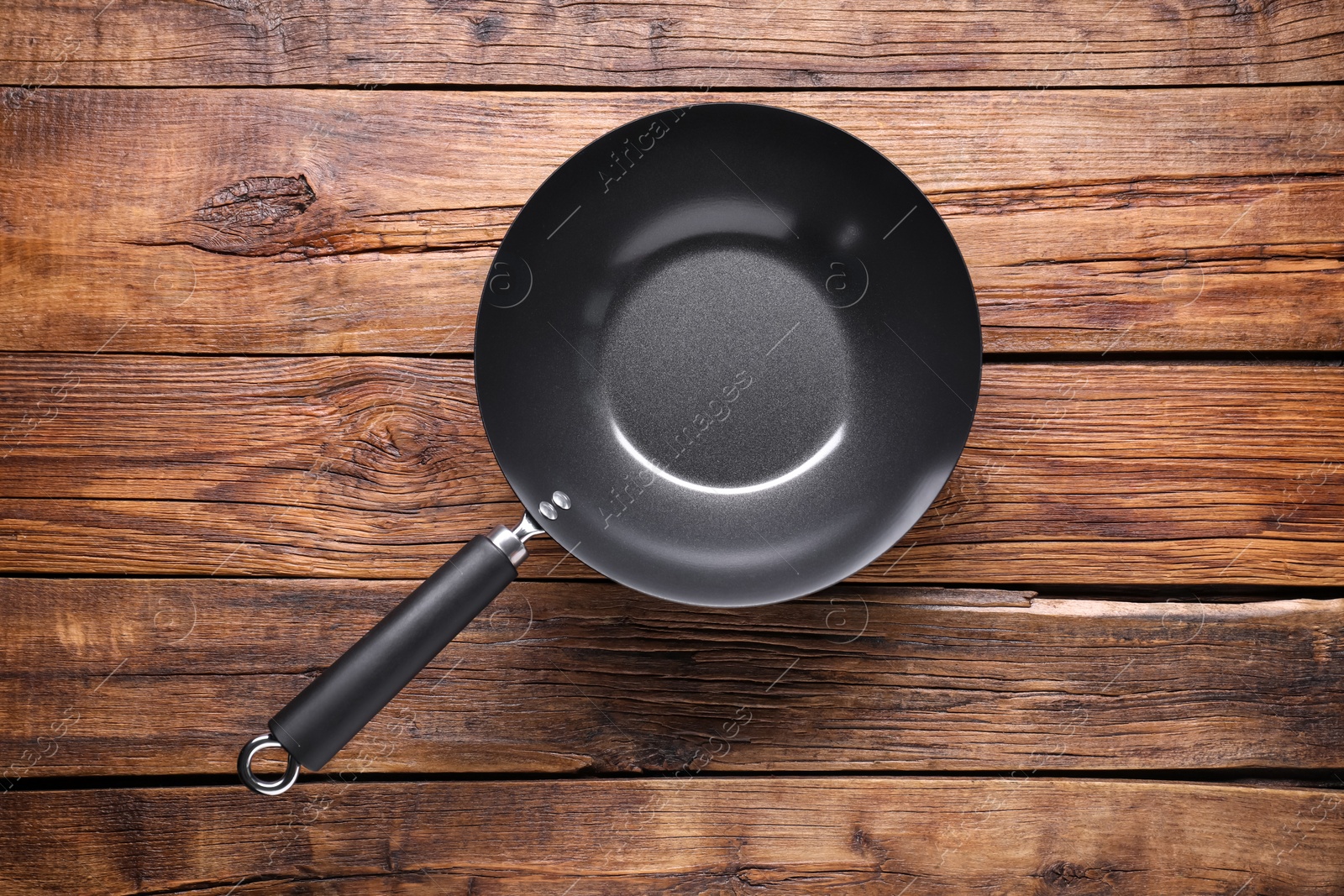 Photo of Empty iron wok on wooden table, top view. Chinese cookware