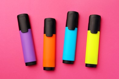 Bright color markers on pink background, flat lay