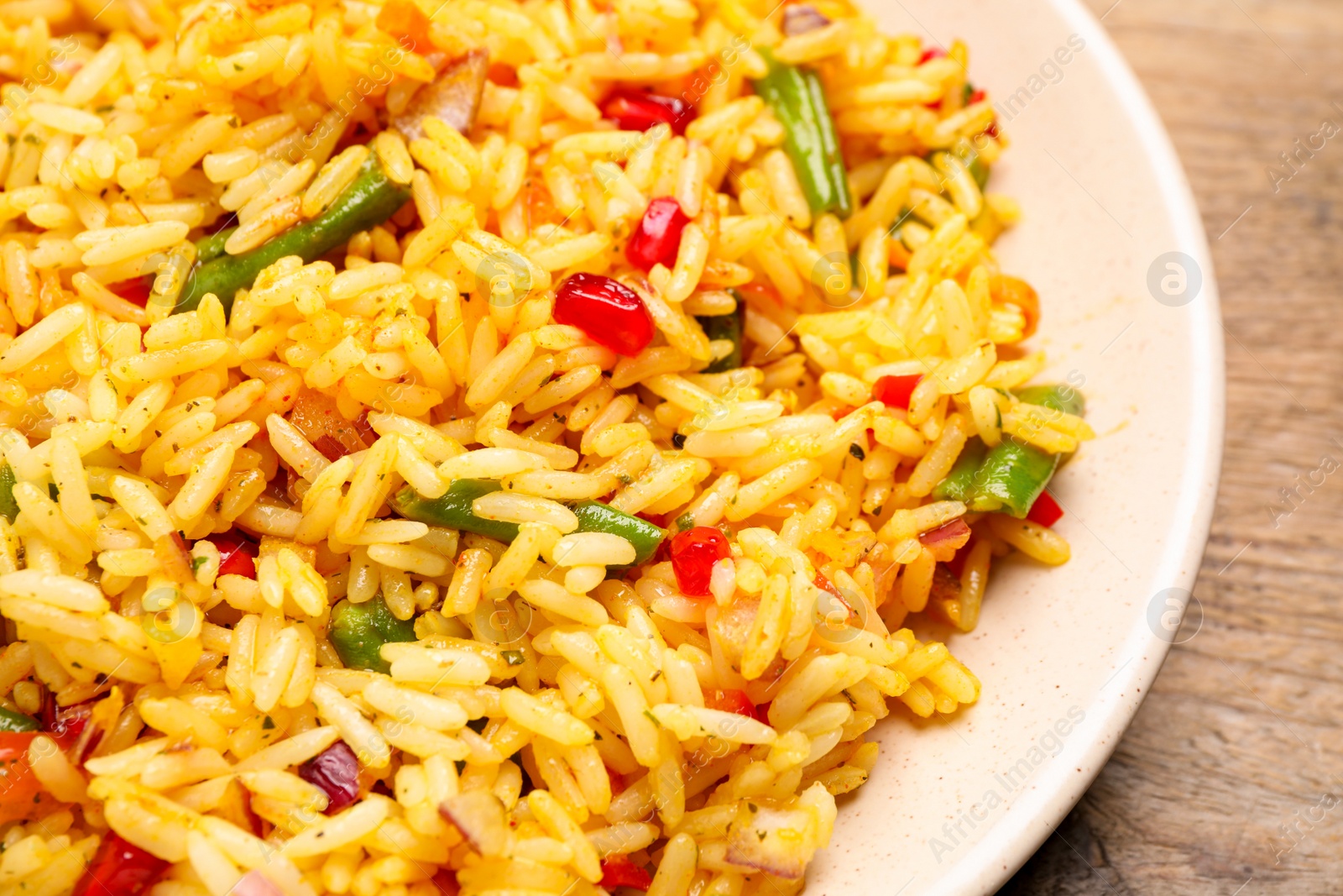 Photo of Tasty rice pilaf with vegetables on wooden table, closeup