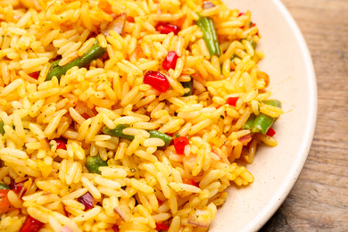 Photo of Tasty rice pilaf with vegetables on wooden table, closeup