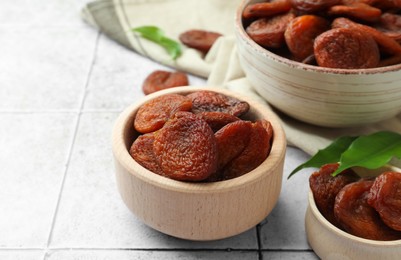 Tasty apricots with leaves on white tiled table, closeup. Dried fruits