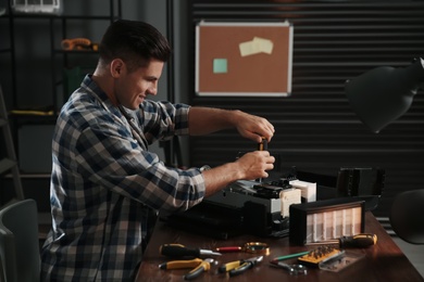 Photo of Repairman with screwdriver fixing modern printer in office