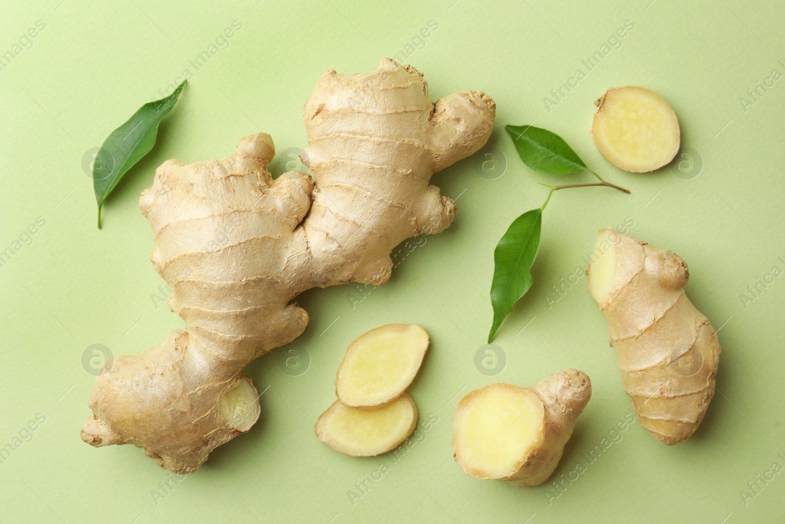 Photo of Fresh ginger with leaves on light pale green background, flat lay