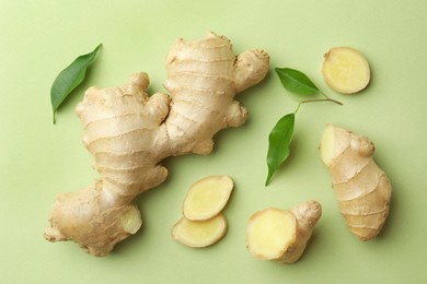 Fresh ginger with leaves on light pale green background, flat lay