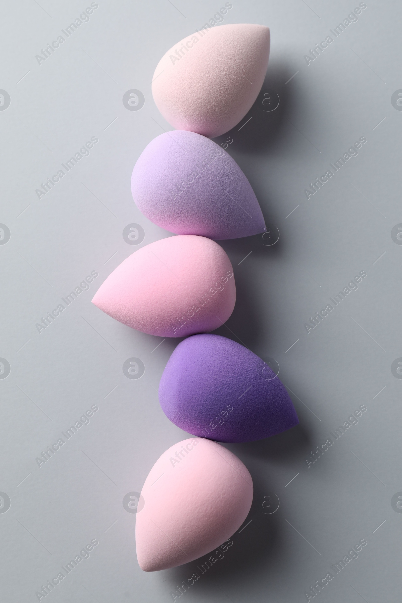 Photo of Many colorful makeup sponges on grey background, flat lay