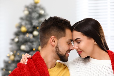 Photo of Happy young couple near Christmas tree at home