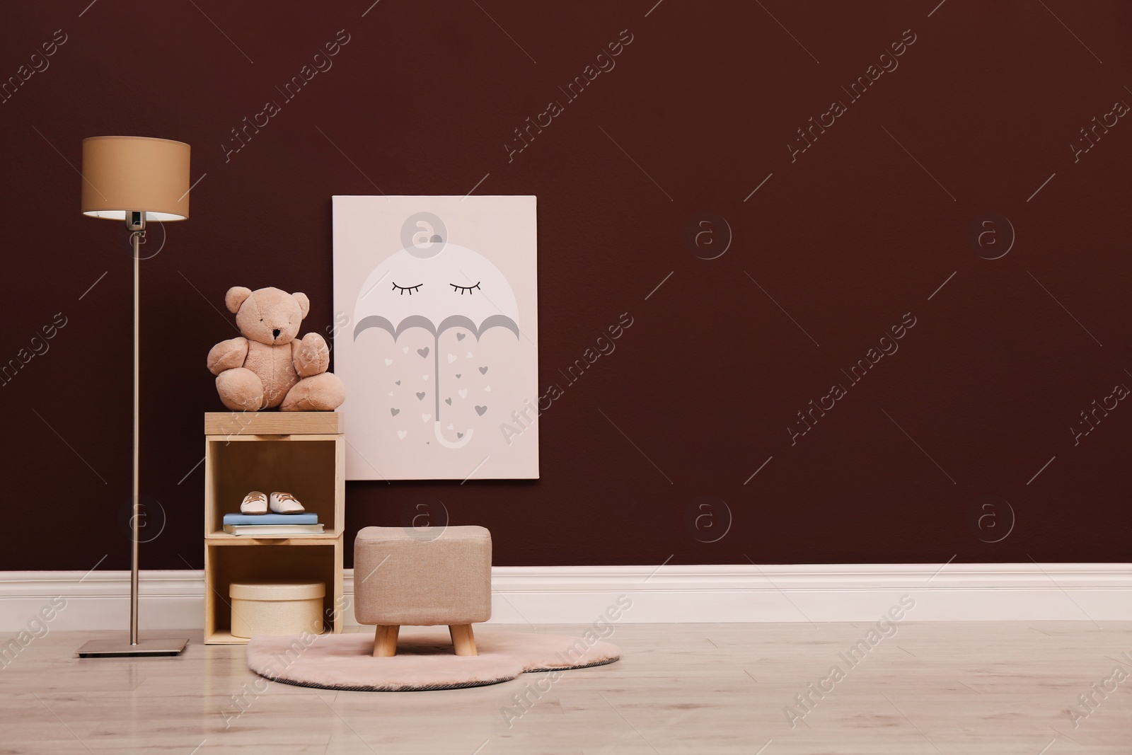 Photo of Stylish beige ottoman, shelving unit with toy bear and lamp in room. Space for text