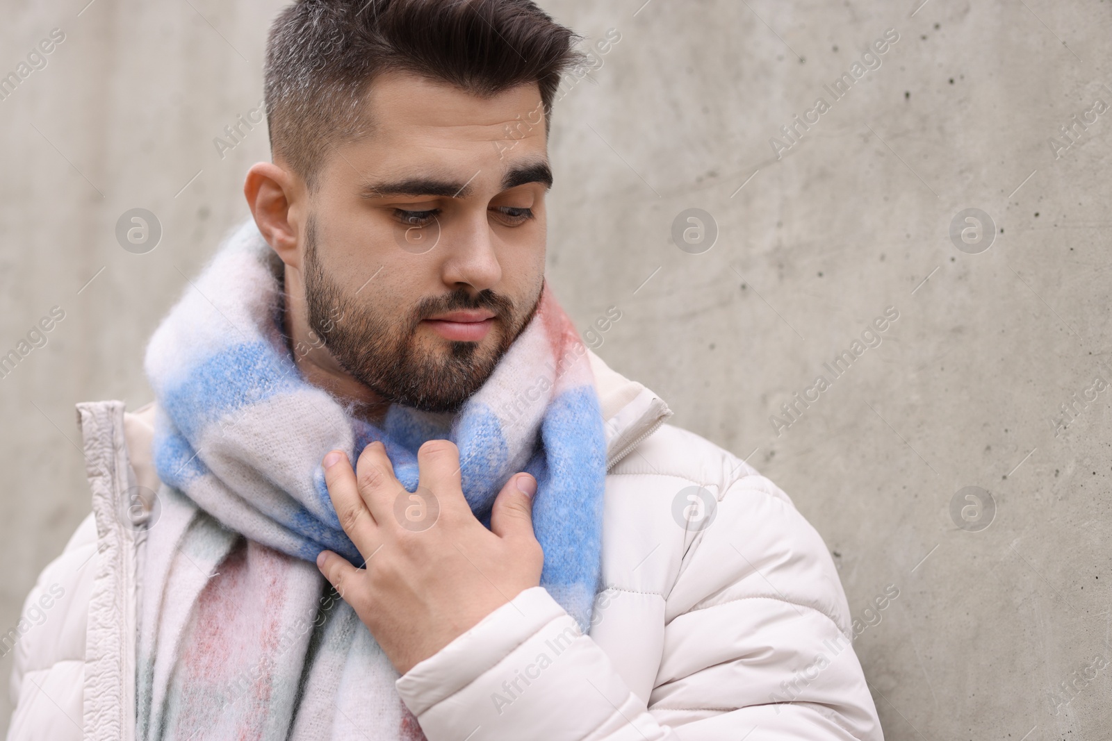 Photo of Handsome man in warm scarf near wall outdoors. Space for text