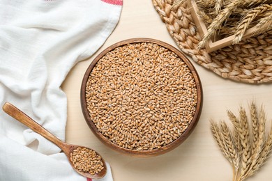 Photo of Wheat grains and spikes on white wooden table, flat lay