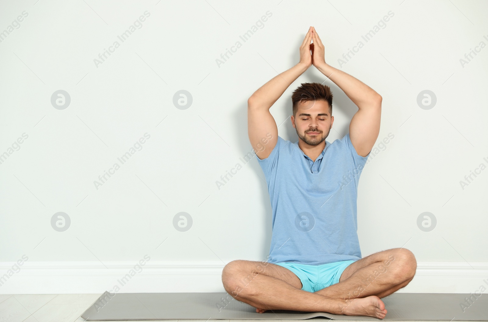 Photo of Young man practicing zen yoga near wall indoors