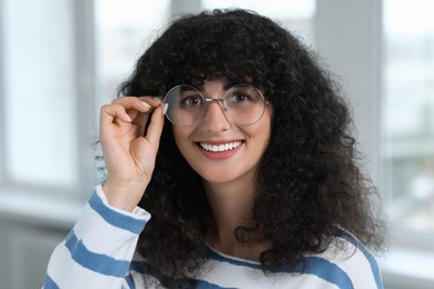 Photo of Portrait of beautiful woman in glasses indoors. Attractive lady with curly hair looking into camera
