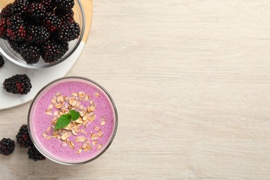 Photo of Delicious blackberry smoothie with oatmeal and berries on white wooden table, flat lay. Space for text