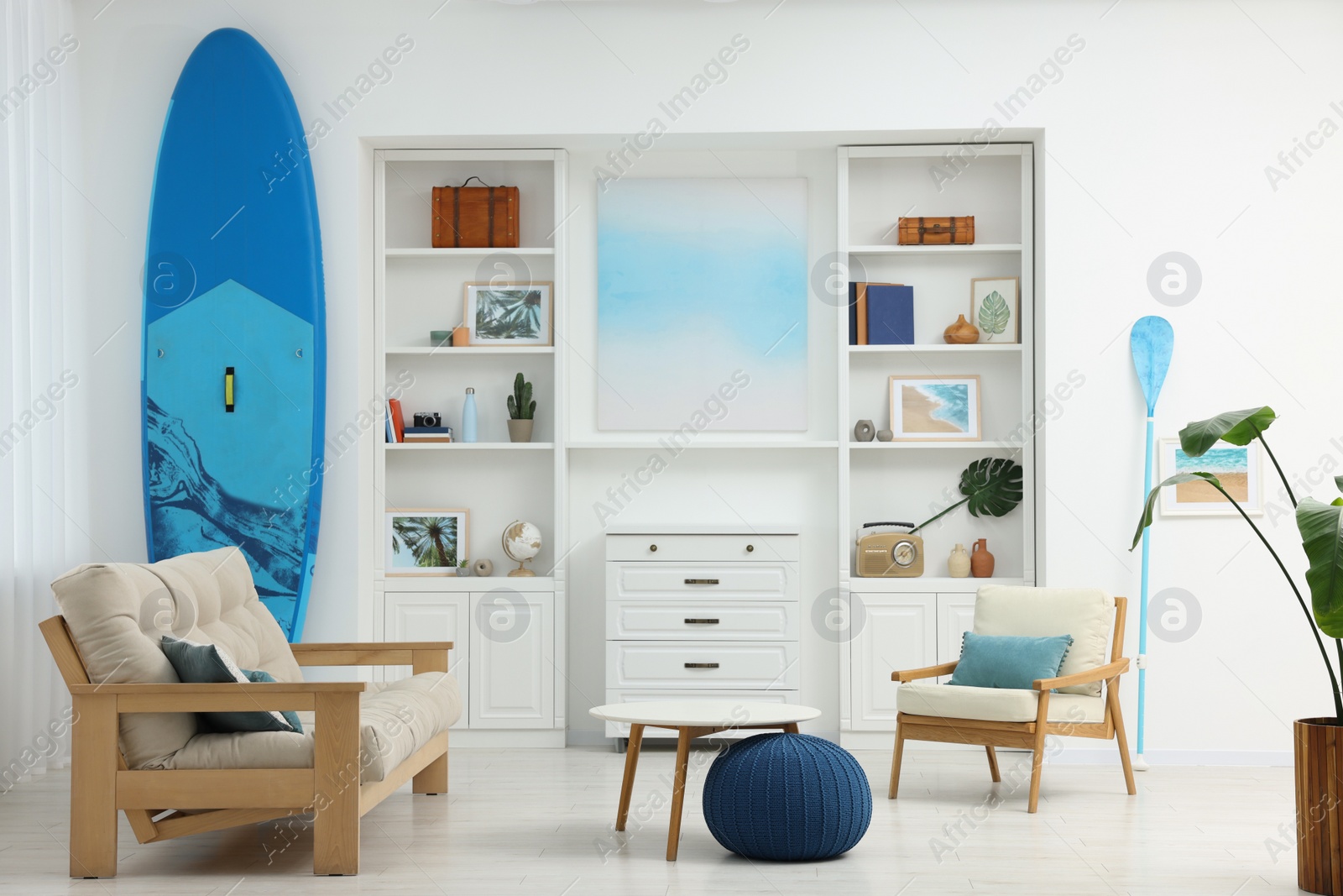 Photo of SUP board and modern furniture in stylish living room. Interior design