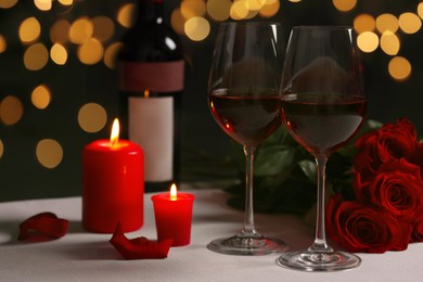 Photo of Romantic table setting with glasses of red wine, rose flowers and burning candles