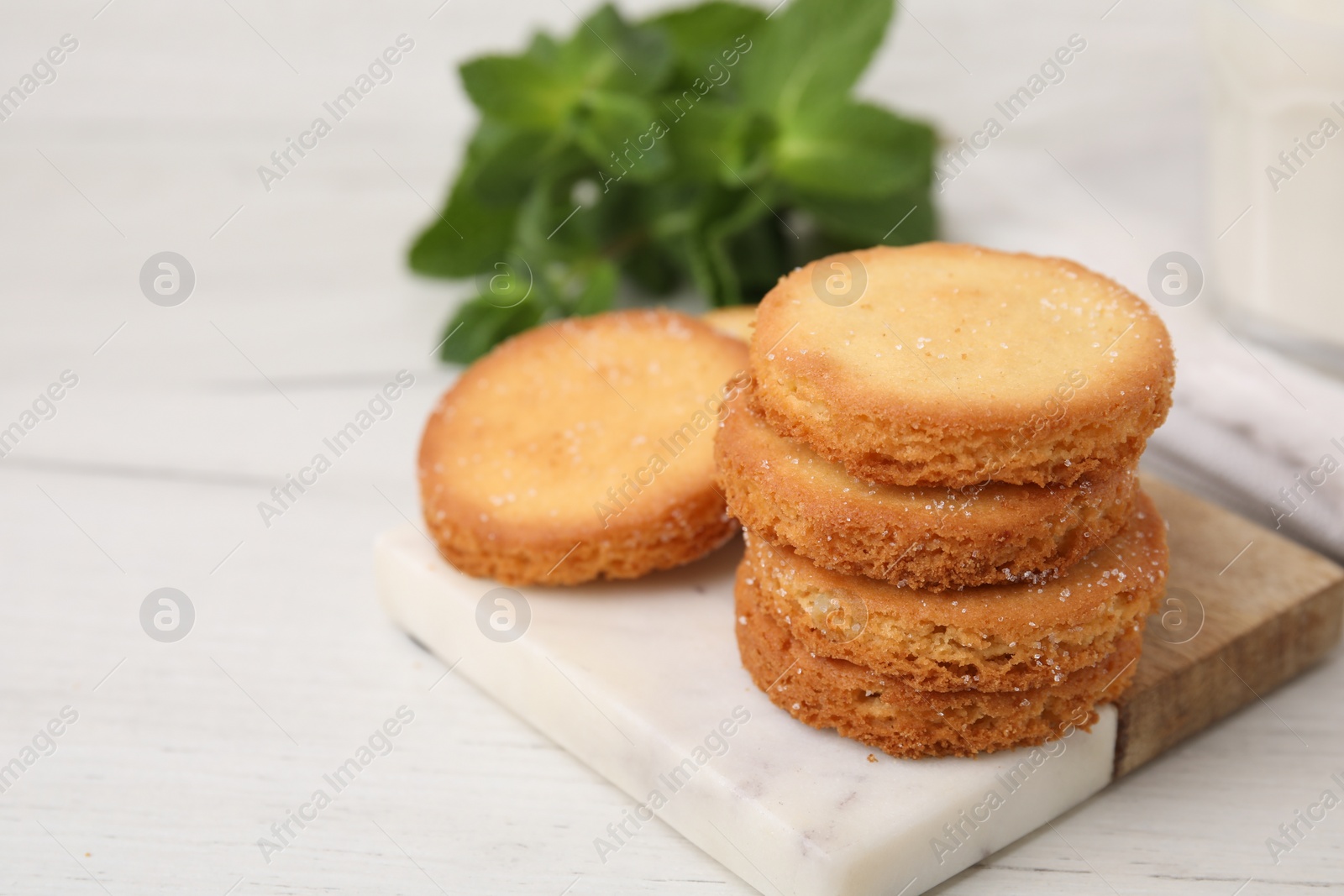 Photo of Tasty sweet sugar cookies and mint on white wooden table, closeup. Space for text