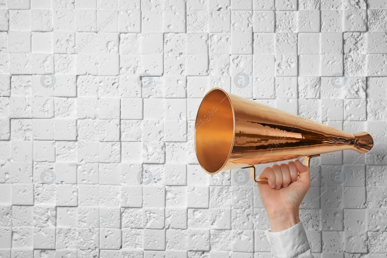 Photo of Woman holding retro megaphone near white wall