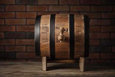 Photo of Wooden barrel with tap on table near brick wall